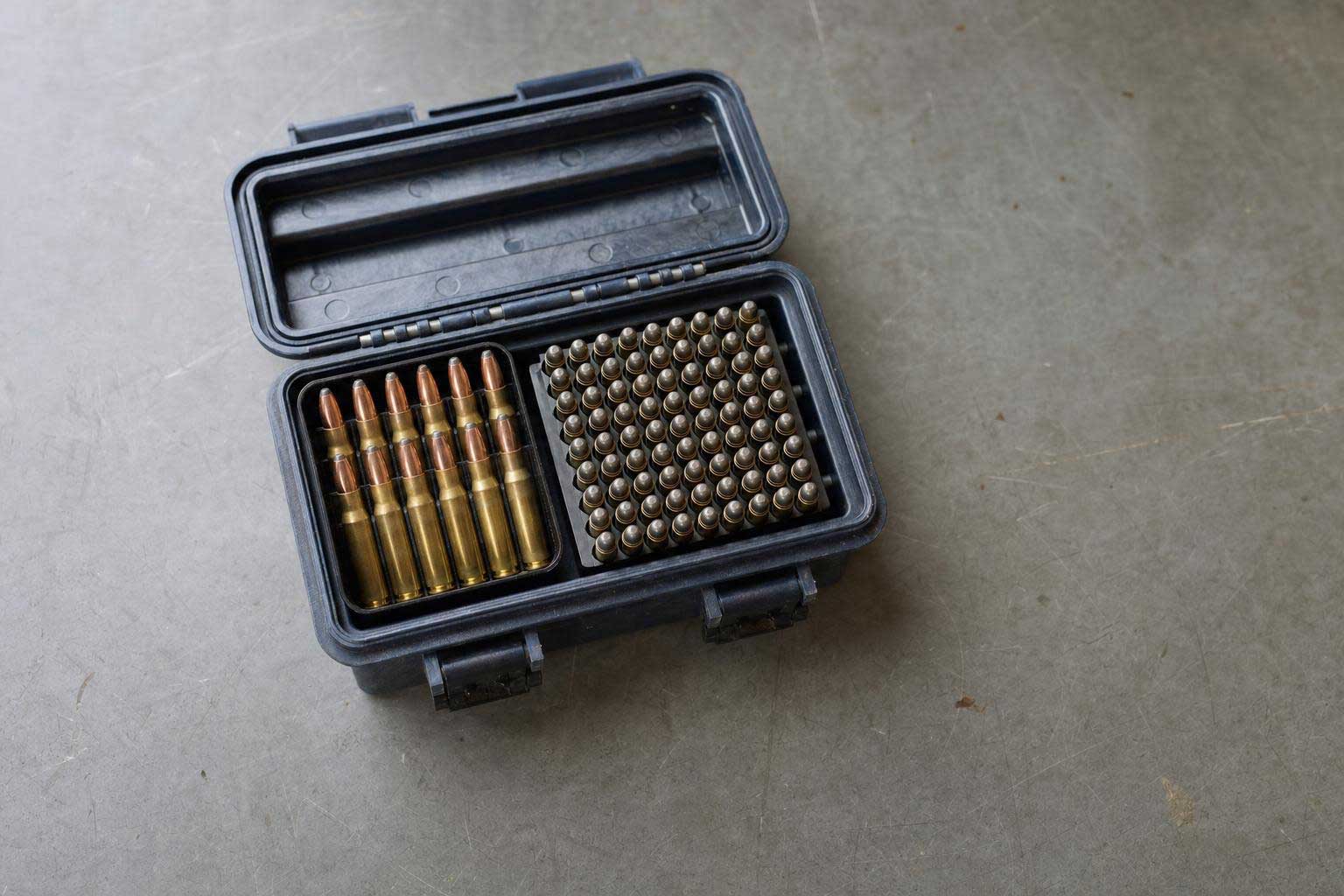 Open black ammunition case containing rifle cartridges and a tray of small-caliber rounds.